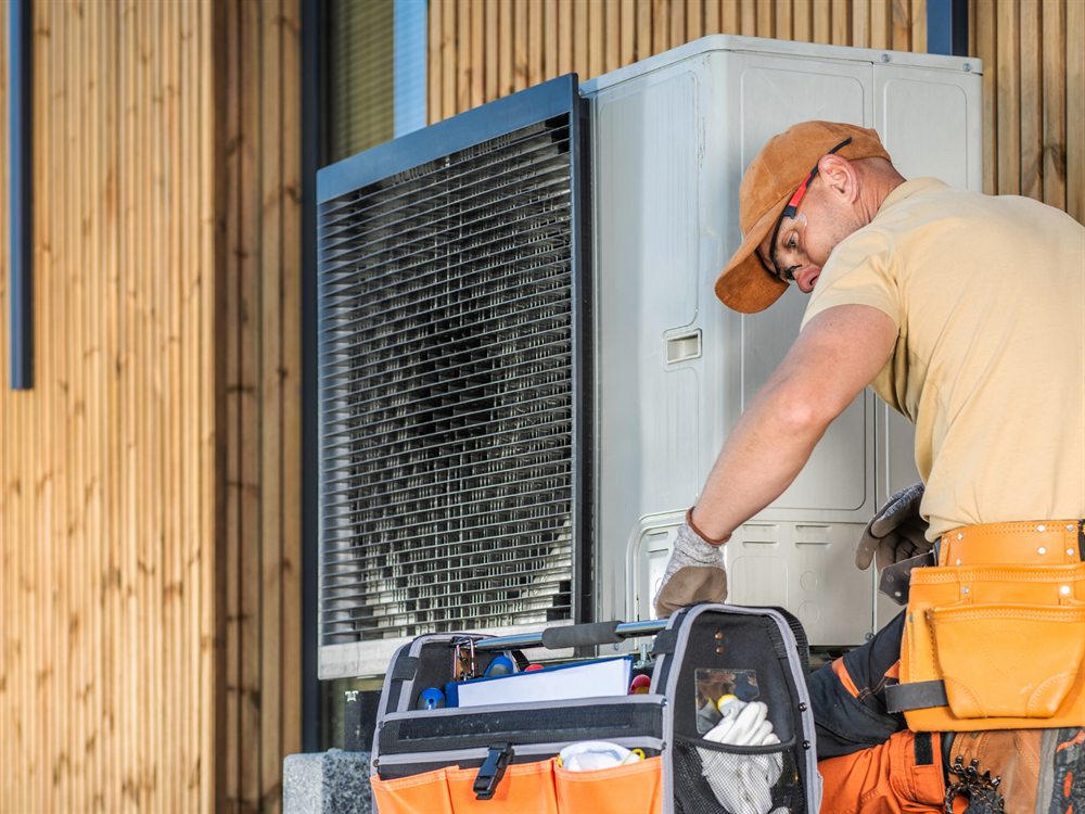 Technicien en appel de service sur une thermopompe, coffre à outils ouvert